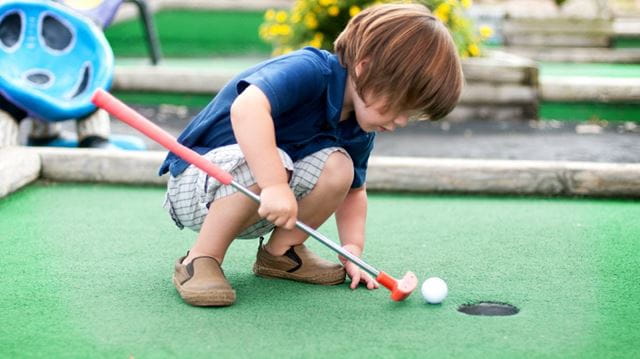 Young child playing mini golf